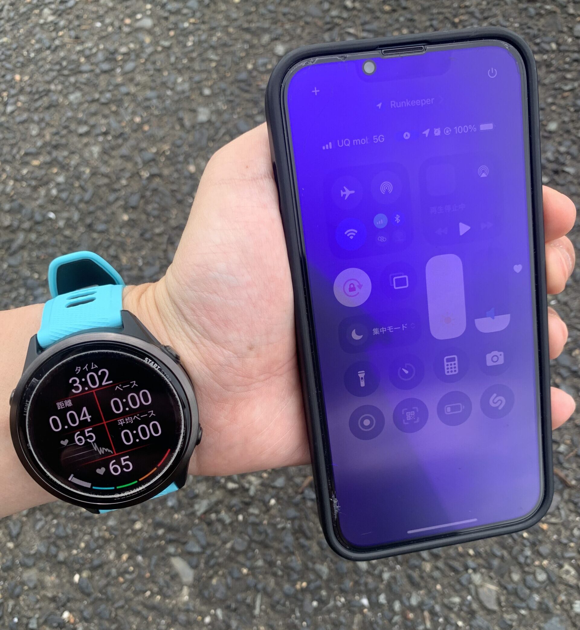 屋外でGarmin 570と明るさを最大に設定したスマートフォンのランニング計測画面を比較している様子